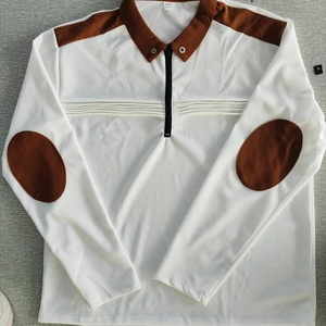 Macro detail of men's polo shirt neckline showing zipper and brown fabric patches