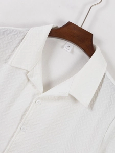 Detail of white textured men's shirt showing the woven fabric and 100% polyester tag