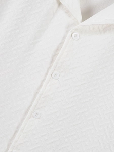 Close-up of white men's shirt showing geometric textured fabric and three round buttons