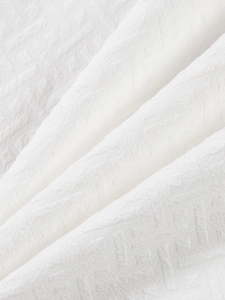 Close-up of white jacquard fabric texture with elegant 3D crinkle patterns for summer sets