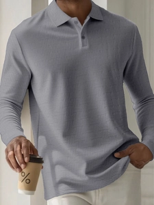 Detailed view of dark gray men's polo shirt featuring waffle knit texture and three-button collar