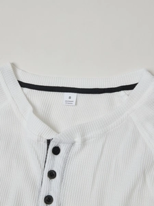 Detail of white waffle knit Henley shirt collar with three black buttons and label