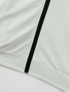 Detail of white stand-collar jacket featuring a contrast black zipper and ribbed hem texture