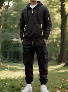 Detail of men's black tracksuit with neon yellow accents and functional cargo pockets