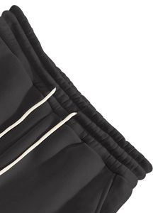 Detailed macro view of the ribbed elastic waistband with cream drawstrings on black joggers