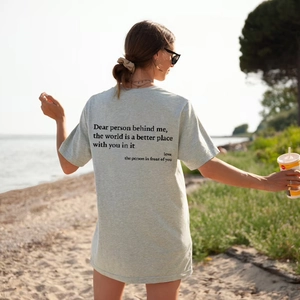 Detail eines hellgrauen Baumwoll-T-Shirts mit Slogan-Print auf dem Rücken am Strand