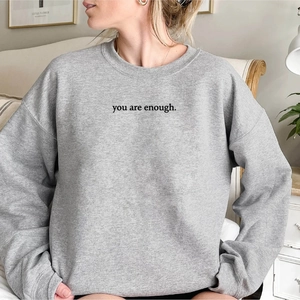Dettaglio della felpa grigia con stampa dello slogan nero 'you are enough' sul petto
