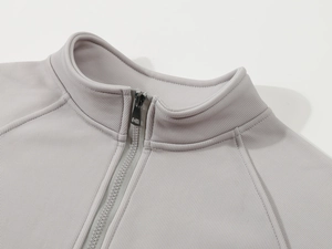 Detail of light grey polo sweatshirt showing standing collar and metal zipper