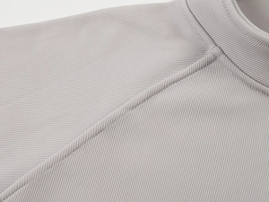 Detail of light gray sweatshirt featuring high-quality diagonal stitching and ribbed texture
