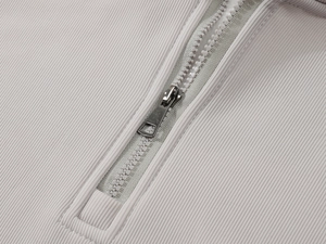 Detail of grey ribbed knit fabric with 1/4 zipper and metallic puller on a men's sweatshirt