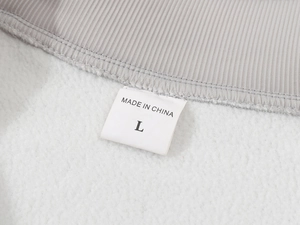 Close-up of soft grey fleece fabric and inner neck label showing size L