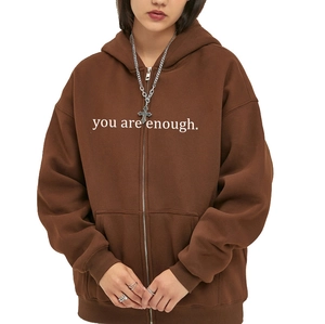 Detail of coffee brown zip hoodie featuring white you are enough slogan and front pocket