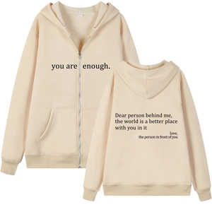 Detail of apricot hoodie showing drawstring hood, front zipper, and printed typography text