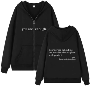 Detail view of black zip-up hoodie featuring white motivational text and kangaroo pockets