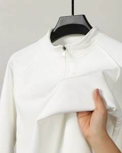 Close-up of white polo sweatshirt fabric showing vertical ribbed texture and elasticity