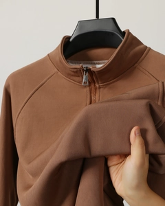 Detail of brown half-zip ribbed fabric showing high elasticity and soft texture