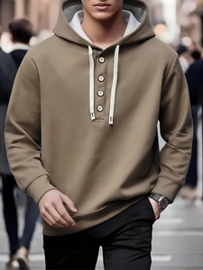 Detail of khaki men's hoodie featuring wooden buttons and grey contrasting hood lining