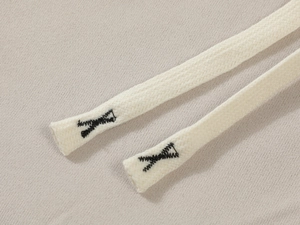 Detailed close-up of hoodie drawstring with black reinforced cross-stitch on beige fabric