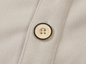 Close-up of a classic engraved button on the texture of a beige premium men's hoodie