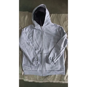 Detail of grey hooded zip-up sweatshirt with front pockets and ribbed cuffs