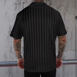 Vista posteriore di una camicia nera a maniche corte con strisce verticali bianche e vestibilità