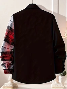 Detail of men's black shirt with a red plaid pattern sleeve on a white wall