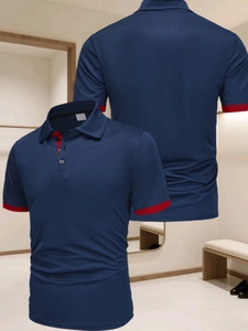 Détail d'un polo de golf bleu marine avec bordures rouges contrastées au col et manches