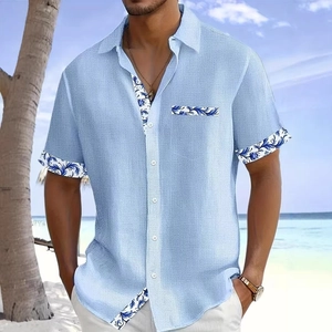 Detail of light blue textured casual shirt with floral patterns on sleeve and pocket