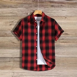 Detail of red and black plaid short sleeve shirt on a rustic wooden background
