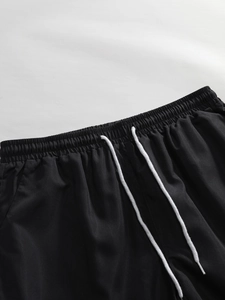 Detailed close-up of black shorts waist with elastic band and white woven drawstrings