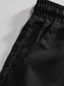 Detail of men's black leisure trousers featuring elastic waist and side pockets
