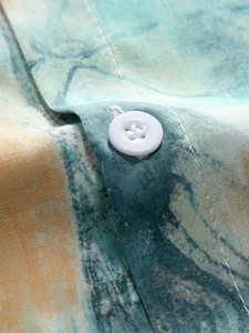 Macro shot of white four-hole resin button on multi-color marble texture fabric