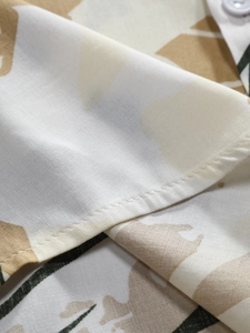 Detail of tropical print fabric with neat stitching and white button on men's shirt