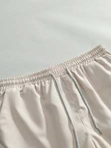 Detail of light beige casual shorts featuring an elastic waistband and round drawstring