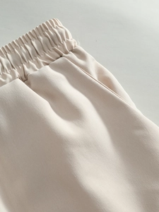 Detail of light beige shorts featuring an elastic waistband and side slanted pocket design