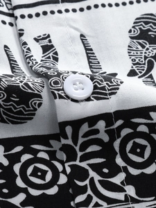 Close-up of elephant ethnic pattern print and white button on cotton shirt fabric