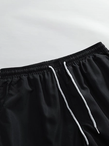 Detail of men's black resort shorts featuring elastic waistband and white braided drawstring