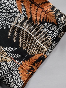 Detail shot of men's resort shirt sleeve showing vibrant orange and black fern leaf prints