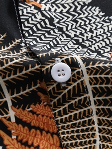 Macro detail of resort style shirt with plant leaf pattern and white resin button