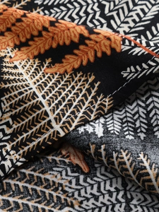 Detailed macro view of black fabric with orange leaf prints and white stitching lines