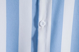 Close-up of blue and white striped fabric with white four-hole button and neat stitching