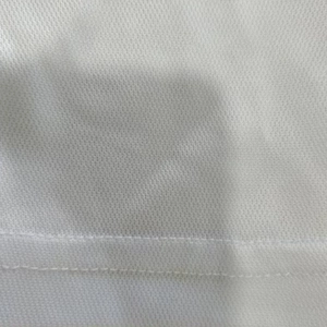Detailed macro view of white mesh polo shirt fabric with double needle stitching at the hem