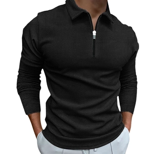 Detail shot of the black waffle knit texture and quarter-zip collar on men's polo shirt