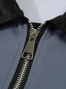 Détail de la fermeture éclair en argent et du col noir sur le polo bleu grisâtre