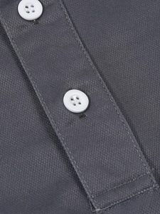 Vue macro du tissu en maille gris anthracite avec boutons blancs sur polo pour hommes