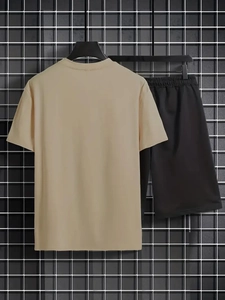 Set casual da uomo con t-shirt beige e pantaloncini neri su una griglia metallica nera