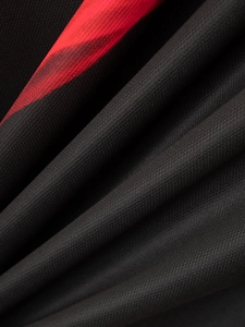 Close-up of black breathable mesh fabric with red pattern detail on a polo shirt