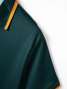Detailed view of dark green polo shirt with breathable mesh fabric and orange contrast trim