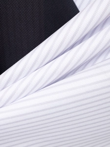 Détail macro du contraste entre le tissu en maille noire et le polo blanc à texture côtelée