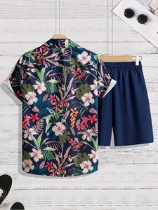 Detail of tropical palm leaf print shirt and navy blue shorts set on white wood background